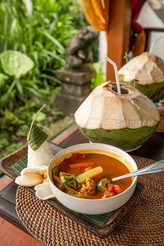 巴厘岛户外餐厅的印尼咖喱鸡配菜Kari Ayam，碗里有蔬菜和椰子